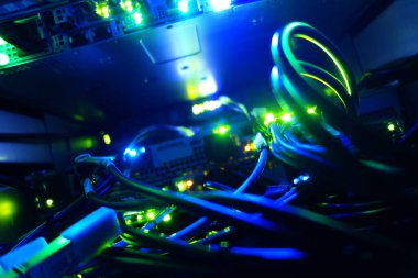 Bir sunucu içindeki renkli kabloların yakın plan görüntüsü, modern teknoloji ve veri bağlantısını gösteren parlayan ışıklar sergiliyor.