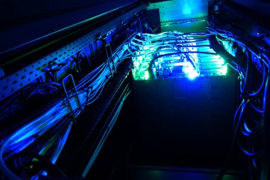 Görsel olarak çarpıcı bir sunucu rafında karmaşık kablolama ve aydınlatılmış mavi ışıklar, gelişmiş teknoloji ve modern veri altyapısı sergileniyor. Teknoloji temalı projeler için mükemmel.