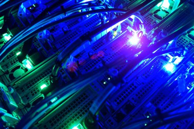 Parlayan mavi LED ışıklar, kablolar ve kabloların yer aldığı, modern teknoloji ve dijital sistemlerin faaliyet halinde olduğu karmaşık bir ağın yakın plan görüntüsü.