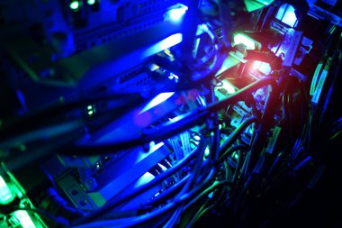 Renkli ışıklarla donanım ve kabloları aydınlatan bir sunucu odasının yakın görüntüsü, faaliyet halindeki teknoloji ve dijital altyapıyı gözler önüne seriyor.