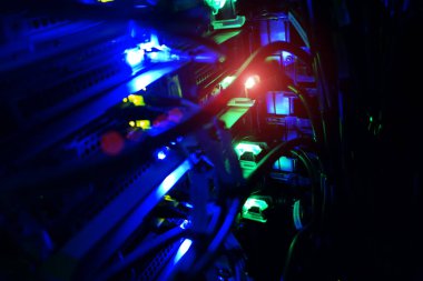 Canlı LED ışıklar sunucu ekipmanlarını aydınlatıyor, karmaşık kablolar ve teknoloji sergiliyor. Ağ oluşturma, veri depolama ve modern altyapı temaları için ideal.