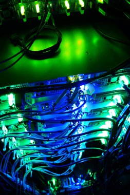 Neon ışıkları ve renkli kablolarla dolu canlı bir sunucu odası teknoloji ve yenilik atmosferi yaratır. Sahne modern veri altyapısının özünü yakalıyor..