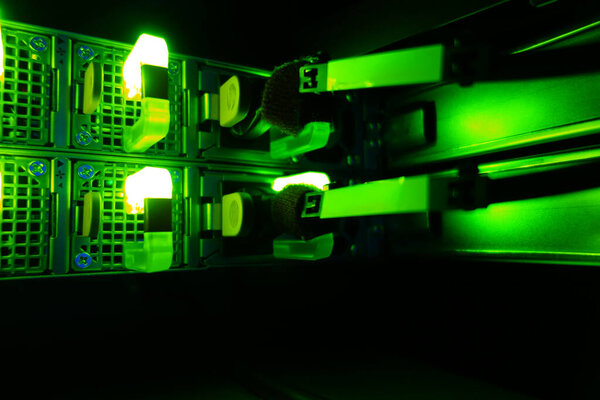 Modern server equipment illuminated by vivid green LED lights, showcasing technology and hardware vital for data management and network systems.