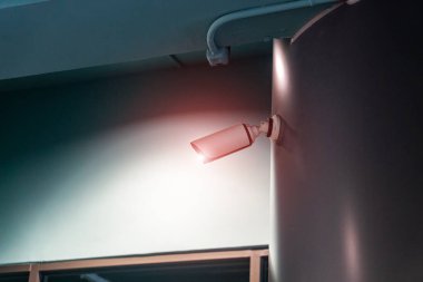 Şık bir duvara monte edilmiş modern bir güvenlik kamerası, uyarı ışığı içeriyor, kentsel çevrelerde güvenlik ve izleme vurgulanıyor.