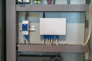 Bu resim çeşitli bağlantılı aygıtlar ve kabloların yer aldığı detaylı bir elektrik kontrol paneli kurulumunu gösterir. Teknoloji ve mühendislik projeleri için ideal.