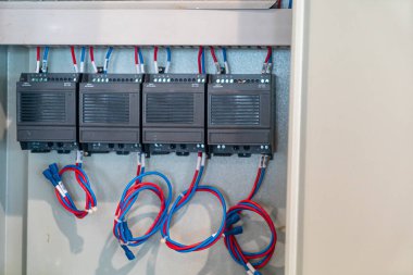 Bu resim, etkili işlem ve kontrol için kablolar ve konnektörlerle titizlikle düzenlenmiş birden fazla aygıtın yer aldığı bir elektrik kontrol panelini gösterir.