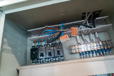 Çeşitli anahtar ve kablolardan oluşan bir elektrik kontrol kutusunun genel görünümü. Bu resim elektrik sistemlerinde kurulum ve bakım için ayrıntılı bileşenleri gösterir.