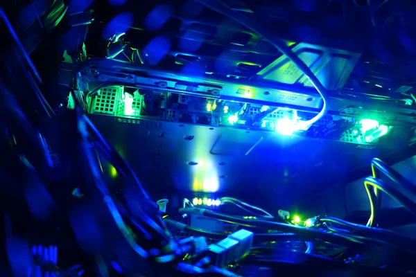 Aydınlatılmış bilgisayar donanımının yakın görüntüsü karmaşık kablolar ve kablolar ortaya çıkarıyor, karmaşık bir elektronik ortamda canlı mavi ve yeşil ışıkları sergiliyor..