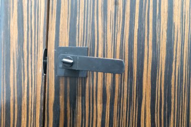 Ahşap bir arka planda basit bir kapı kilidi mekanizması. Resim işlevsellikle birlikte ahşabın dokusunu ve tasarımını gösteriyor.