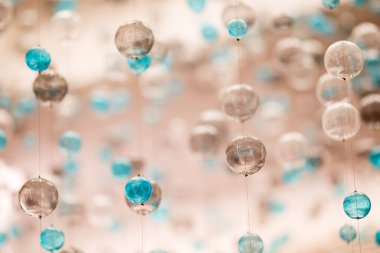 Bu büyüleyici görüntü, mavi aksanlı renkli asılı kürelerin çarpıcı bir düzenini gösteriyor. Işık ve camın etkileşimi, modern iç tasarım için mükemmel, tuhaf bir atmosfer yaratıyor..