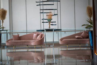 Modern bir iç mekanda yerleştirilmiş sofistike pembe bir kanepe. Gösterişli tasarım ve zarif yansıma uzayın atmosferine ve genel estetiğine eklenir.