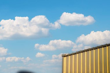 Doğadaki modern mimarinin güzelliğini gözler önüne seren tüylü beyaz bulutlarla dolu parlak mavi gökyüzüne karşı çarpıcı bir altın bina..