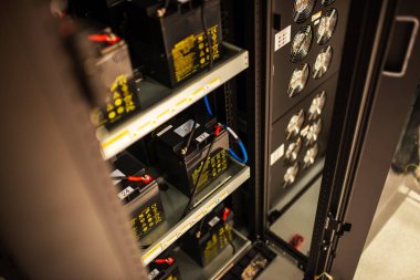 Bu resim modern bir sunucu odasında enerji yönetimi ile ilgili karmaşık bağlantıları ve teknolojiyi vurgulayan güçlü pil depolama çözümleri sergiliyor.