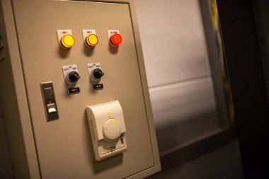 Endüstriyel bir ortamda makine işlemleri ve elektrik ayarlarında kullanılan çeşitli anahtar ve düğmelerin yer aldığı bir kontrol panelinin yakın görüntüsü.