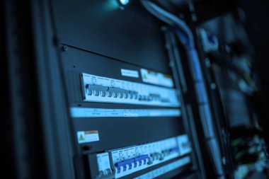 Bir veri merkezi içindeki ağ ekipmanlarının yakın çekimleri, modern teknoloji ve bağlantı çözümlerini destekleyen kablolar ve paneller sergileniyor.