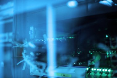 Parlak mavi ışıkları ve karmaşık kabloları olan büyüleyici bir sunucu odası manzarası. Resim, veri yönetiminde gelişmiş teknoloji ve modern altyapıyı sergiliyor.