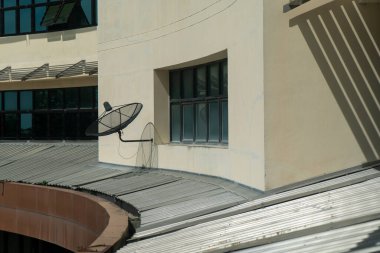 Bir bina duvarına monte edilmiş modern bir uydu anteninin yakından görüntüsü, şehir mimarisi ve teknolojisini açık hava ortamında sergiliyor.