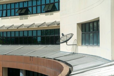 Modern bir binanın dış yüzeyine monte edilmiş bir uydu anteninin yakın görüntüsü. Görüntü mimari tasarım, teknoloji entegrasyonu ve kentsel estetiği vurguluyor.