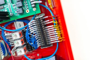 Kablo bağlantıları, elektronik bileşenler ve canlı kırmızı evler içeren karmaşık bir devre kartının ayrıntılı görünümü, teknoloji ve mühendislik temaları için ideal.