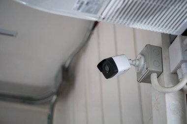 Beyaz bir duvara güvenli bir şekilde yerleştirilmiş bir güvenlik kamerası gözetleme ve izleme yeteneği sağlıyor. Cihaz çeşitli ortamlarda güvenliği ve korumayı artırır..