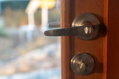 Yumuşak güneş ışığını yansıtan modern bir kapı kolunun yakın çekim görüntüsü. Görüntü kapı donanımının parlak tasarımı ve kaliteli materyallerini gösteriyor.