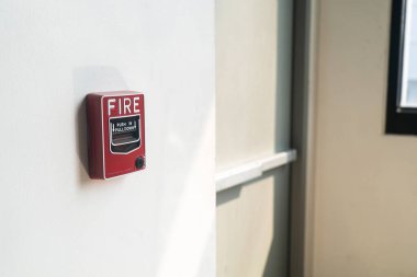 Görüntü bir yangın alarmı düğmesini içerideki bir duvarda gösteriyor. Cihazın parlak kırmızı rengi personel için açık bir acil durum alarmı görevi görüyor..