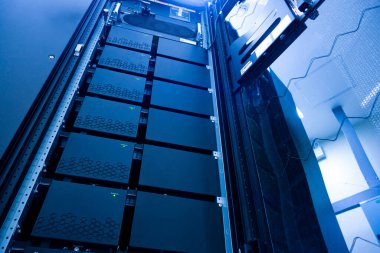 Bir veri merkezinde gelişmiş donanımla dolu yüksek teknoloji sunucu rafı, mavi ışıkla aydınlatılmış, verimli veri yönetimi için modern teknoloji sergileniyor.