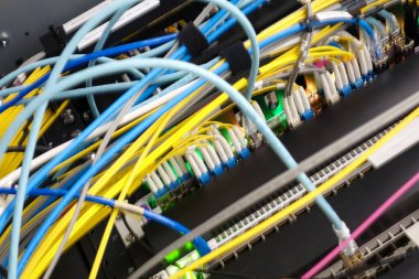 Bir sunucu odasında birbirine dolanmış renkli ağ kablolarının yakın plan görüntüsü, veri bağlantısı ve iletişim için gerekli modern teknoloji ve altyapıyı sergiliyor.
