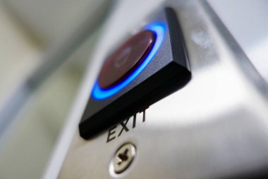 Bu yakın plan resim modern bir çıkış düğmesi içeriyor, parlak metal tasarımı ve aydınlatma kenarları, güvenlik işareti ve mimari kullanım için ideal.