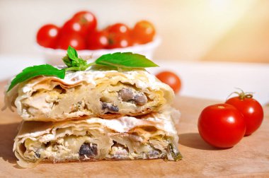 Ev yapımı tavuk turtası. Tavuk eti ve mantarla doldurulmuş taze lezzetli turta. Tahta tabakta servis ediliyor, domates ve fesleğen ile.