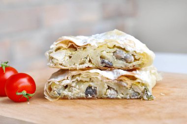 Ev yapımı tavuk turtası. Tavuk eti ve mantarla doldurulmuş taze lezzetli turta. Tahta tabakta servis ediliyor, domates ve fesleğen ile.