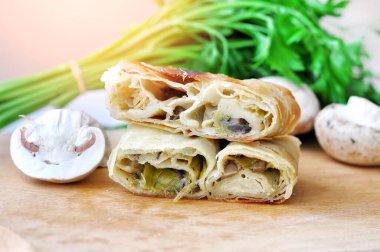 Ev yapımı mantar turtası. Tahta bir tabakta, mantarlar ve maydanozla servis edilen pırasa ve mantarla doldurulmuş taze lezzetli turta.