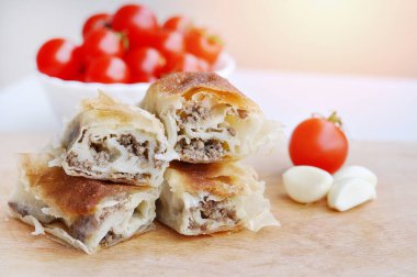 Ev yapımı etli turta. Tahta tabakta servis edilen domuz etiyle doldurulmuş lezzetli turta, sarımsaklı ve domatesli.