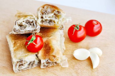 Ev yapımı etli turta. Tahta tabakta servis edilen domuz etiyle doldurulmuş lezzetli turta, sarımsaklı ve domatesli.