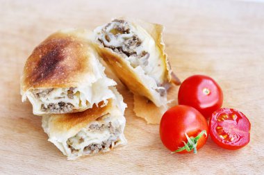 Ev yapımı etli turta. Tahta tabakta servis edilen domuz etiyle doldurulmuş lezzetli turta, sarımsaklı ve domatesli.