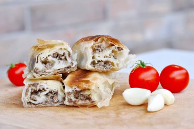 Ev yapımı etli turta. Tahta tabakta servis edilen domuz etiyle doldurulmuş lezzetli turta, sarımsaklı ve domatesli.