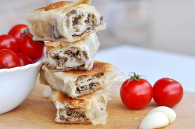 Ev yapımı etli turta. Tahta tabakta servis edilen domuz etiyle doldurulmuş lezzetli turta, sarımsaklı ve domatesli.