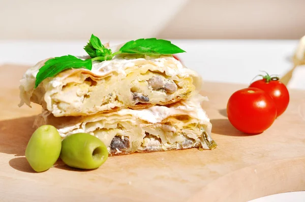 Ev yapımı tavuk turtası. Tavuk eti ve mantarla doldurulmuş taze lezzetli turta. Tahta tabakta servis ediliyor, domates ve fesleğen ile.