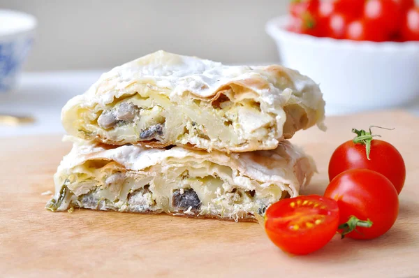 Ev yapımı tavuk turtası. Tavuk eti ve mantarla doldurulmuş taze lezzetli turta. Tahta tabakta servis ediliyor, domates kirazlı..