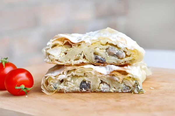 Ev yapımı tavuk turtası. Tavuk eti ve mantarla doldurulmuş taze lezzetli turta. Tahta tabakta servis ediliyor, domates ve fesleğen ile.