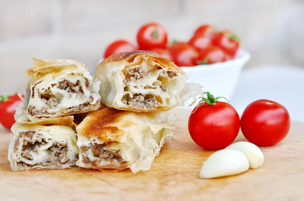 Ev yapımı etli turta. Tahta tabakta servis edilen domuz etiyle doldurulmuş lezzetli turta, sarımsaklı ve domatesli.