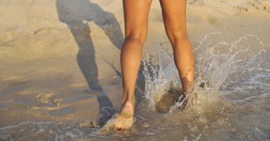 Plajda kadın bacakları, yaz zamanı konsepti.
