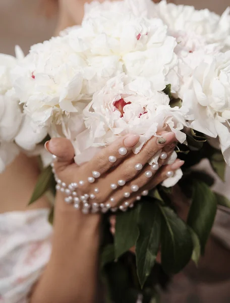 Female hand with decoration of pearls on flowers. Wedding photography concept.