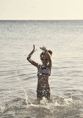 Küçük kız denizde eğleniyor. Çocukların tatildeki duyguları. Yaz zamanı konsepti.