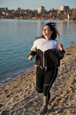 Kumsalda koşan güzel bir genç kadın. Fitness konsepti. Kadın dışarıda egzersiz yapıyor..