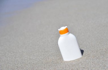 Kum dokusunda güneş koruması kremi olan bir şişe..