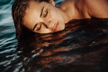 Gün batımında sahilde poz veren güzel bir kadının portresi..