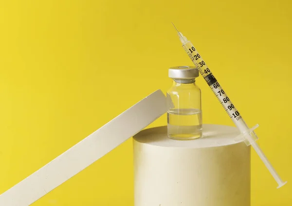 黄色の背景に表彰台に輝きとアンプル 予防接種の概念 — ストック写真