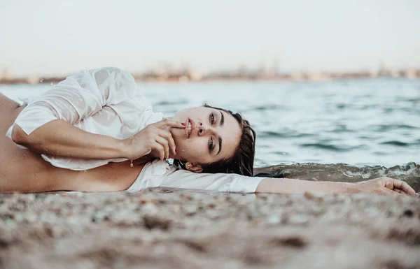 ビーチにポーズを白いシャツの美しい女性 日没時にポーズをとる若い美しい女性 夏時間の概念 — ストック写真