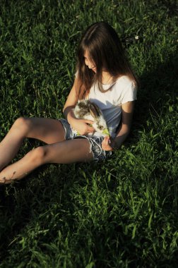 Kız küçük sevimli bir tavşana sarılıyor. Paskalya 'nın tavşan sembolü. Çocuk ve hayvan konsepti arasındaki arkadaşlık.